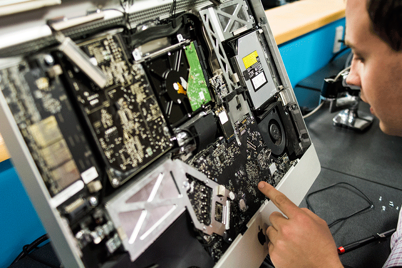 Mac technologist Jeremy Fernie searches for signs of water damage behind the screen of an Apple desktop that bore the brunt of a flood last week.