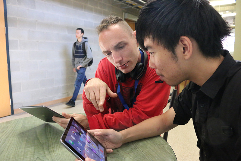 Donald James, Media fundamentals student, left and Donny Jun Man having a conversation with their iPads.