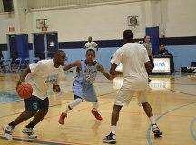 An alumni player brings the ball past half-court.
