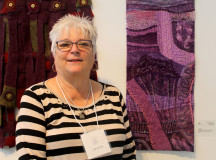 Chris Booth standing next to her own fibre art creation on the right. (Photography by Courtney Blok / The Sheridan Sun)