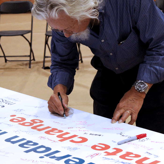 Suzuki signs a Mission Zero banner that Sheridan's sustainability group put together. The sign read "I pledge to support Sheridan in the fight against climate change."
