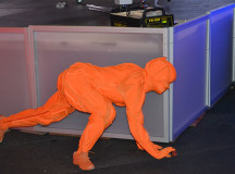 A ninja dressed in orange silently sneaks around the stage. 